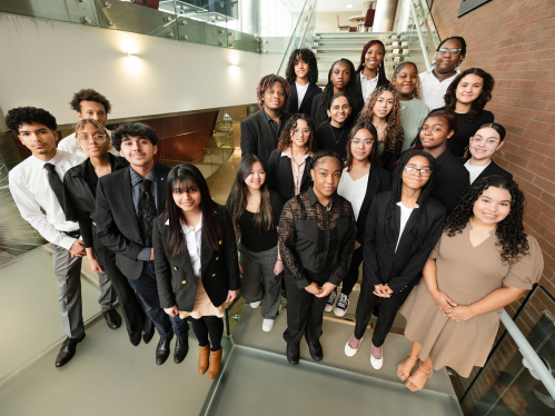A group of students in business attire standing on the steps in the Rutgers Business School building on Livingston Campus