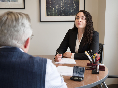 A female business professional sitting at a round table with another male professional