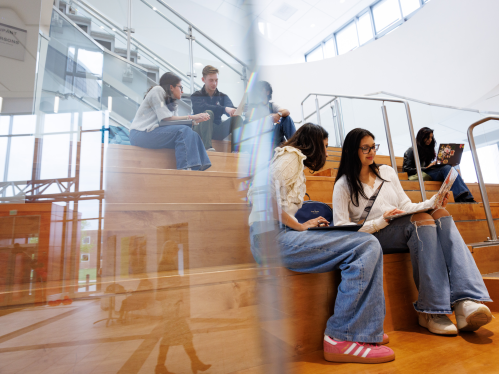Students talking and looking at their computers in a common area