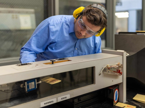 Wearing earmuffs and safety glasses, Rutgers-New Brunswick senior Doug Doyle operates and miniature wind tunnel in a School of Engineering lab on Busch campus.