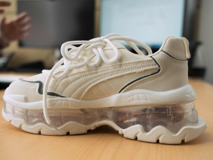 A white sneaker with electronics in its nearly see-through heel.