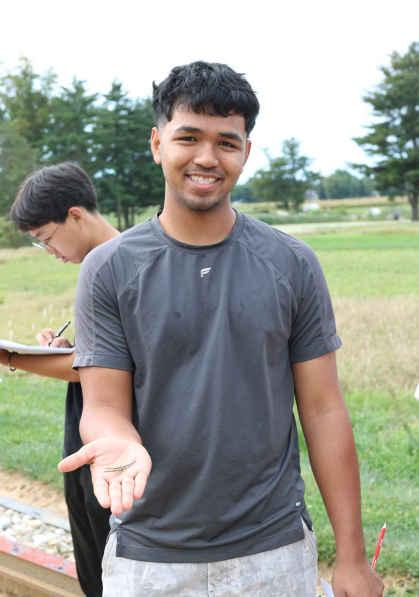 Rutgers Honors College student Foysal Sorwar displays blades of grass at Adelphia Farm.