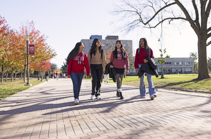 Four students wearing Rutgers shirts walk on Livingston Campus.