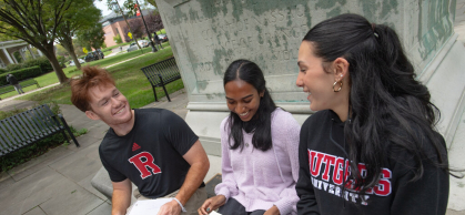three students seated together talking and smiling