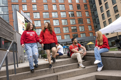 Students in Rutgers attire walking down and sitting on steps
