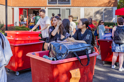 Students rolling their belongings in large red bins during move-in 2026