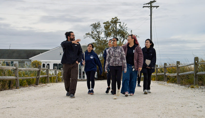 A group of people walk together on a road covered with crushed clam shells.