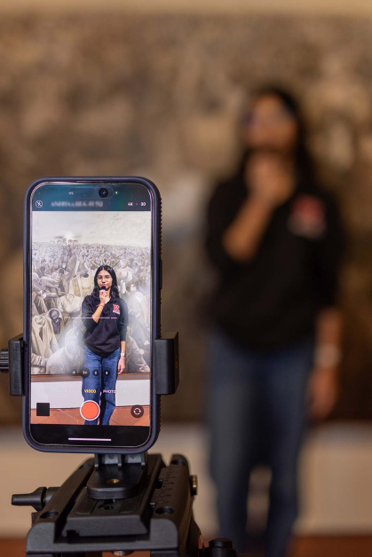 A smartphone records Rutgers sophomore Aditi Sandhir talking about a painting on the wall at the Zimmerli Art Museum.