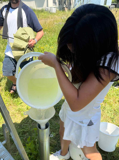 Rutgers student Charlene Guo adds uranine (a fluorescent dye) dissolved in water into a well to track groundwater flow in June,