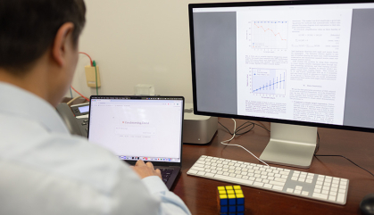 Man facing computer screen laptop and desktop with equations on them.