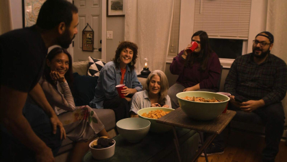 A group of adult friends play a party game in a living room in a scene from "Frankie's Okay."