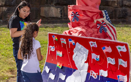 Jessie Garcia speaks with a girl looking at a collaborative mural featuring a map of New Jersey.