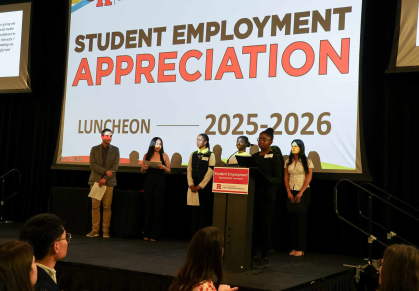 Under the watch of administrator Bill Kelly (left), Jada Harris speaks at the podium during a luncheon at Livingston Hall in April.
