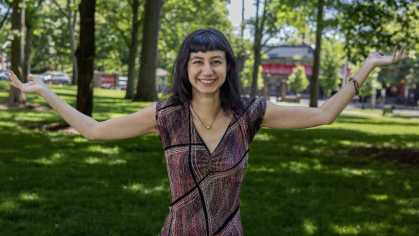 Jane Teran smiles and hold out her arms while standing in the grass on Voorhees Mall.