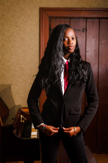 Rutgers senior Latisha Lubega stands next to a piano in a dramatically lit room.
