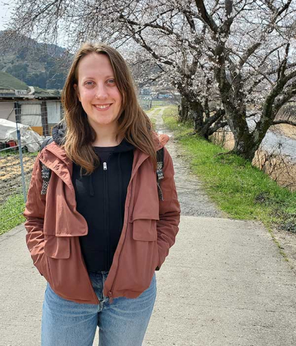 Woman standing outside with trees behind her