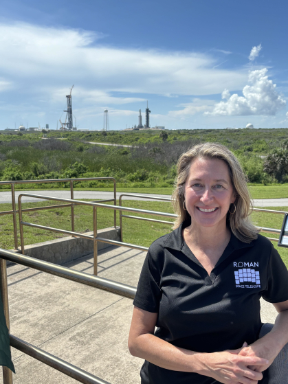 Woman stands out in the bright sunshine at NASA's Cape Kennedy with the rocket launch assembly behind her