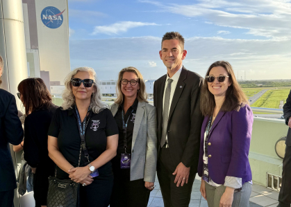A group of four people stand in front of a NASA rocket at Cape Kennedy in Florida.