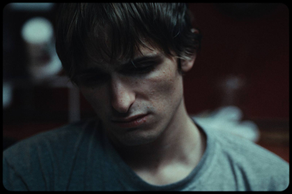 A scene from "My Plastic Lung" depicts a despondent young man looking down. 