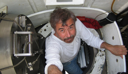 Scientist in white shirt is climbing out of a research submarine