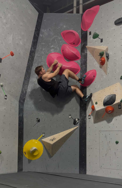 Rutgers graduate Christopher Slipiec scales a rock wall in an indoor space in Warsaw.