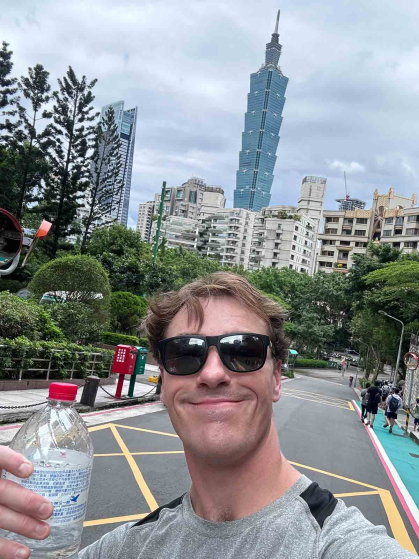 Standing before a view of skyscraper Taipei 101, Rutgers graduate Jack Wooks snaps a selfie before starting to walk the Elephant Mountain trail.