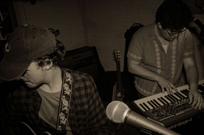 Members of Lawns, one with a guitar near a mic and one on keyboards, perform.