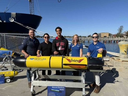 Teledyne employees. Rutgers professor Joe Gradone and student Mason Diaz stand behind the Redwing glider before its launch Oct. 10 in Woods Hole, Mass.