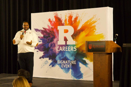 William “Wil” Jones holds a mic and speaks on stage during a student and employer networking dinner held in Livingston Hall in March.