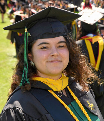 Young woman wearing cap and gown during graduation ceremony from SEBS