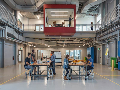 Students work on projects together in a central high ceilinged interior space.