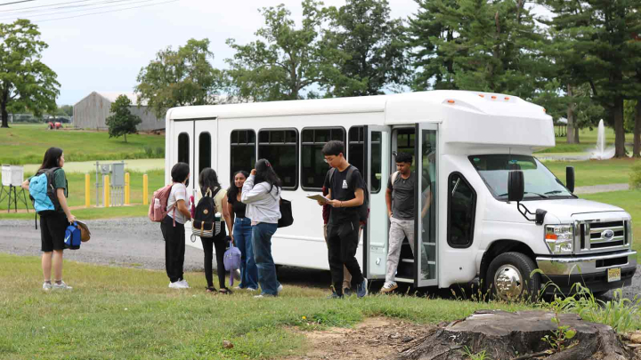 Rutgers Honors College students descend from a white shuttle on Rutgers Honors College students evaluate experimental turfgrass varieties on Adelphia Farm.