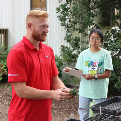 Rutgers graduate assistant Ryan Earp (left) explains how to separate grass roots during an exercise as Honors College sophomore Anny Noh looks on.