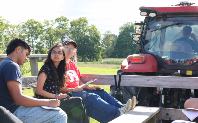 Honors College students Foysal Sorwar (left), Prisha Shah and Jen Kim ride in a wagon towed by a tractor at Snyder Farm.