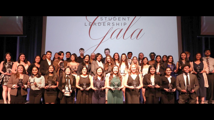 A large group of students standing on a stage holding awards