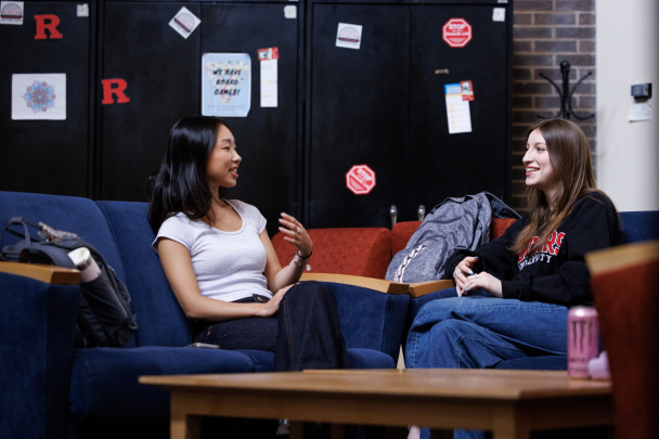 Two students sitting on couches and talking in the Busch Commuter Student Lounge