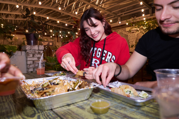 Kelsey Shaw, Brandon Silva and a group of students eating nachos and tacos in Downtown New Brunswick