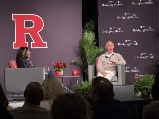 Chancellor Conway and Peter Seligmann sitting on a stage in front of a big red R