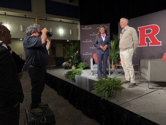 Chancellor Conway and Peter Seligmann posing for a photo on a stage in front of a big R