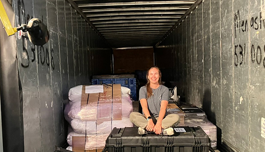 Student sits atop cargo in a freight truck