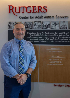 Daniel Muhlbach poses and smiles inside the Rutgers Center for Adult Autism Services.