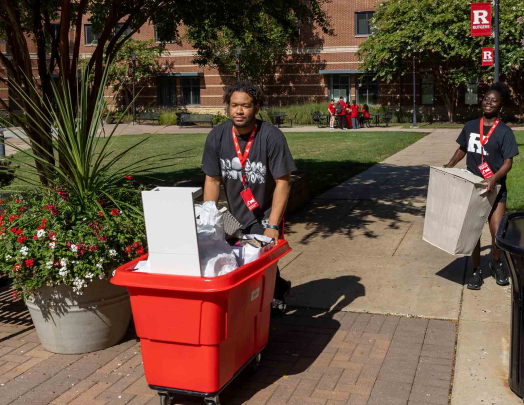 A move-in volunteer pushes a red cart Monday outside of BEST Hall.