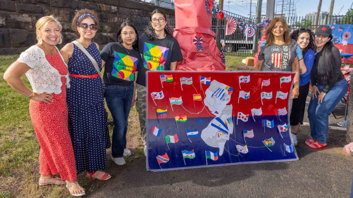 Seven women pose behind a handmade mural featuring New Jersey during the Wash and Learn end-of-year celebration event in New Brunswick in early June..