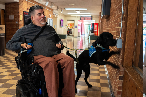 Gonzalo the service dog helps open a door for Javier Robles