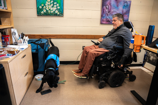 Javier Robles with is service dog who is picking up his cell phone