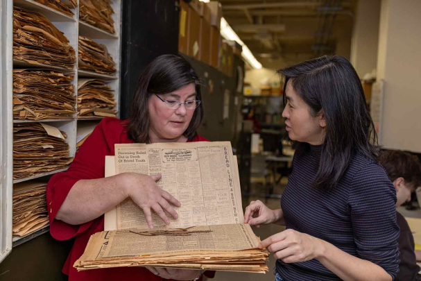 Lena Struwe, director of the Chrysler Herbarium, shows Sue Huang a plant specimen stored between sheets of newsprint.