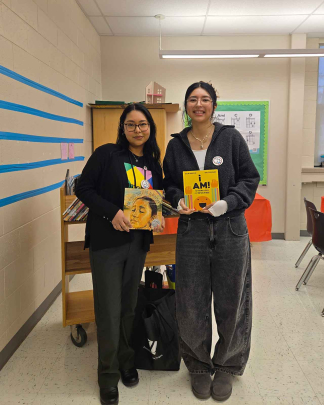 Jessie Garcia (left) and Hanna Cherres hold up children's books in the Paul Robeson Community School for the Arts in New Brunswick.
