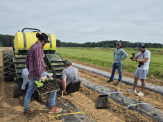 Rutgers School of Environmental and Biological Sciences researchers standing in a field next to a tractor